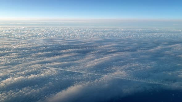 Incredible view from the cockpit of an airplane flying high above the clouds leaving a long white co