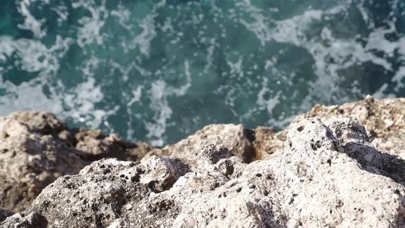 Slow motion reveal of a rough sea under a rocky cliff