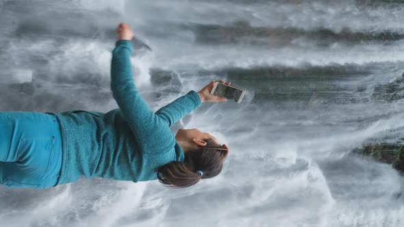 Female Tourist Taking Photos of Waterfall