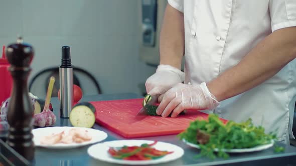 Cook Cuts a Fresh Cucumber for a Salad with a Knife