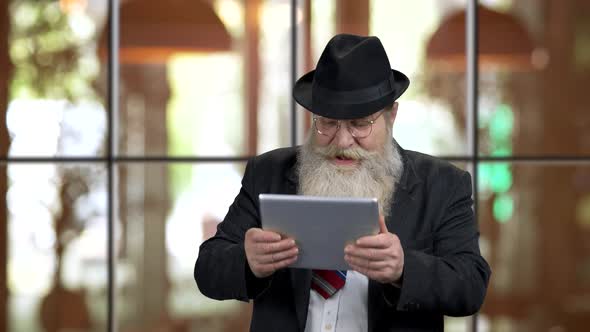 Old Bearded Man with Tablet Pc Is Extremely Excited