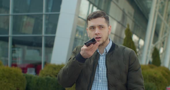 Man Using a Smartphone Voice Recording Function Online Walking on a City Street, Talking To Mobile