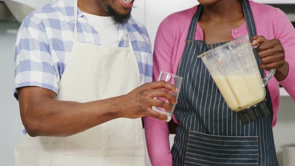 Happy man and woman preparing juice in juicer