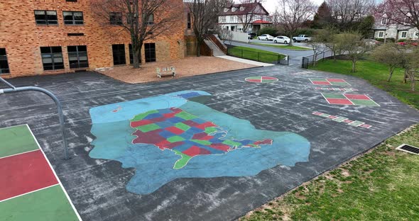 Aerial of school in community. View of playground at recess and approach USA map painted on asphalt