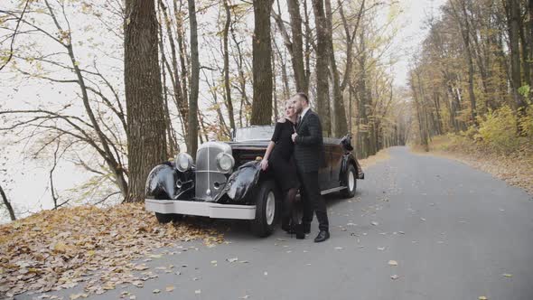 Portrait of Happy Couple Stands in Embraces at Car and Looks Into the Distance