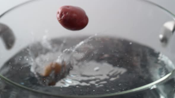 Camera follows cooking potatoes in boiling water. Slow Motion.