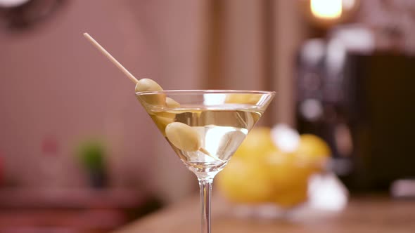 Close Up Parallax Shot of a Martini Glass Garnished with Olives