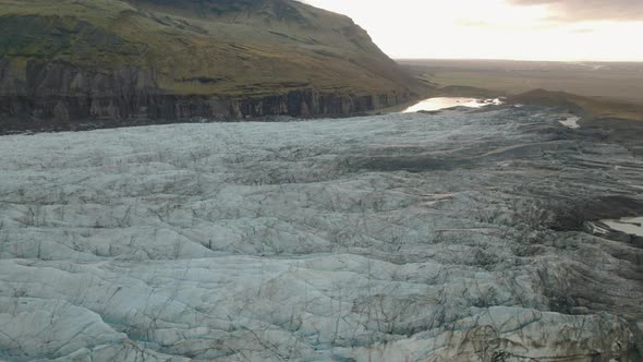 Aerial tilt up over glacier revealing valley and mountains at sunset. Ireland.