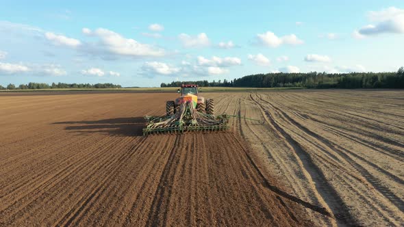 Farmer In Tractor Sows Seeds In Soil Of Agricultural Field On Spring Day Aerial