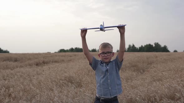 Happy guy with a toy airplane on a wheat field in the sunset light.