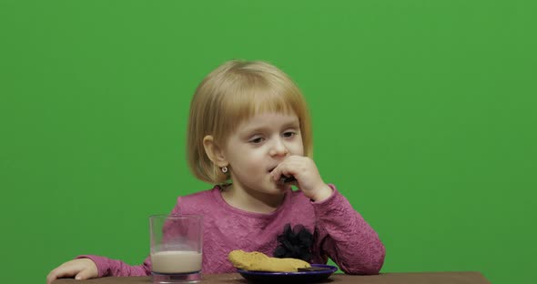 Girl Sitting at the Table and Eating Chocolate, Cookies and Drinks Cacao