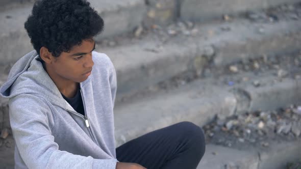 Sad Poor Teenager Looking at Coins in Hand Sitting Outdoors, Urban Unemployment