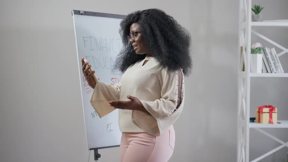 Positive Busy African American Woman Talking at Smartphone Video Chat Walking in Office Indoors