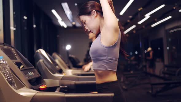 Young beautiful asian woman running on a treadmill at gym.