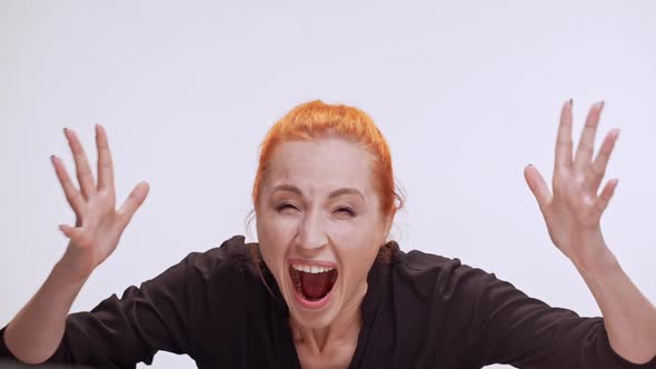 Very Angry Middleaged Caucasian Female with Colored Orange Hair Screaming at Camera Holding Hands