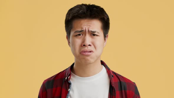 Upset Asian Guy Posing Expressing Sadness Posing Over Orange Background