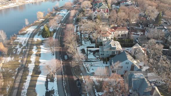 aerial footage following a car on a nice neighborhood, road by the lake shores during a sunny aftern