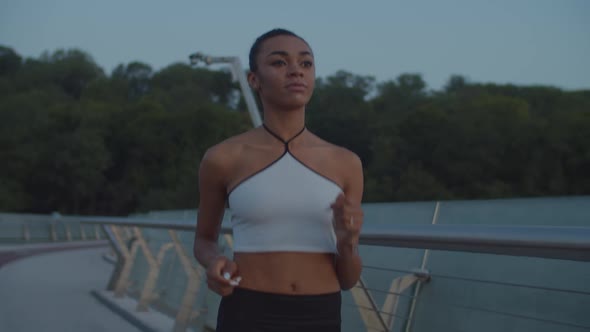 Sporty Fit Woman Jogging on Bridge in Morning Glow