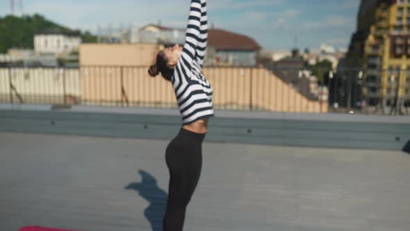 Woman Doing Yoga Exercises on House Roof in Early Morning