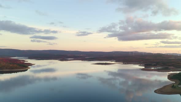 Drone aerial view of a lake reservoir of a dam with perfect reflection on the water of the sunset in