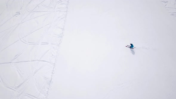 Aerial of ski resort at sun mountains with pine forest. Skiers ride down on snow slope at lifts. Win