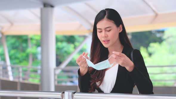 Business woman cough then pick hygiene mask to cover her face to prevent the spreading of virus