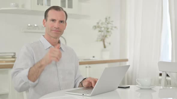 Positive Middle Aged Man with Laptop Doing Thumbs Up