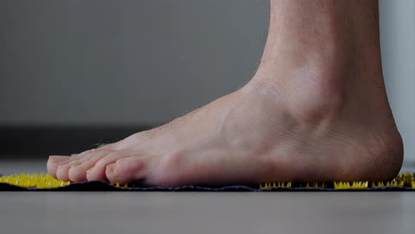 Men's Feet Barefoot on a Massage Mat