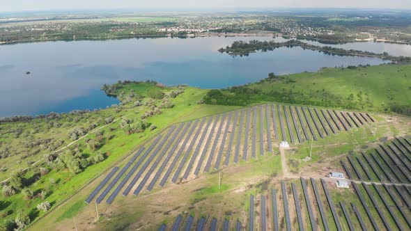 Aerial View on Solar Power Station in Green Field Near River at Sunny Day