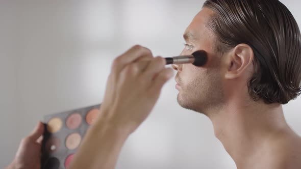 MUA Putting Bronzer on Face of Male Model