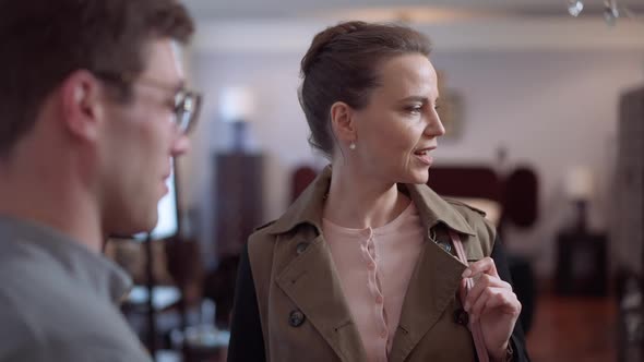 Portrait of Confident Wealthy Smiling Caucasian Woman Talking with Man in Furniture Store Choosing