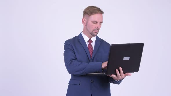 Happy Blonde Businessman Thinking While Using Laptop