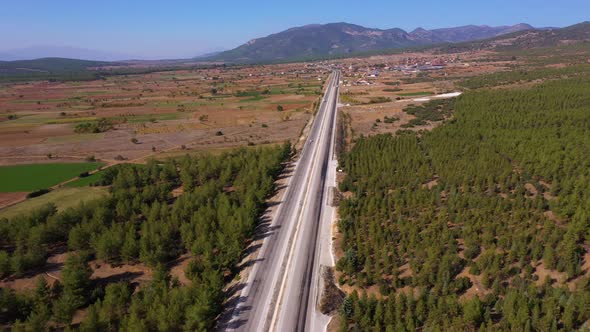 Aerial View of Rural Road Among Forest with Mountains in the Background