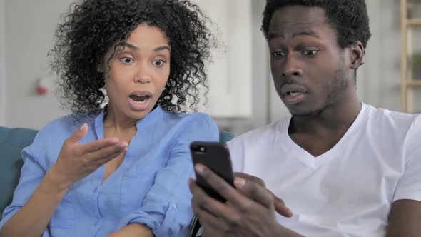 Shocked African Couple Using Smartphone