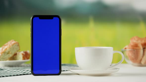 Smartphone with Blue Chroma Key Screen and Tea Cup Closeup