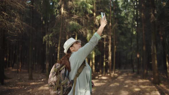 Traveler Woman in a Hat Trying To Catch a Cell Signal on the Phone in the Forest, No Signal on the