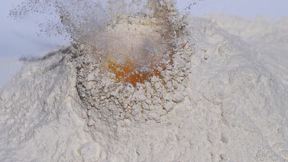 700018 Egg falling into flour against white background, Slow motion