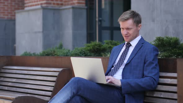 Excited Businessman Celebrating Success, Working on Laptop