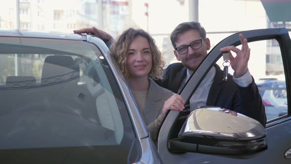 Portrait of Happy Car Purchaser, Young Couple Lovers Delight New Vehicle and Showing Keys in Auto