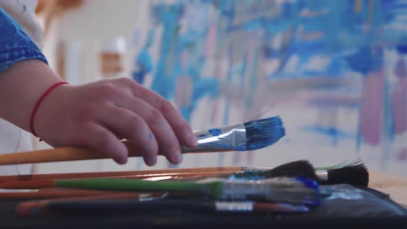 A Woman Paint Artist Drawing an Abstract Blue Painting with Brushes