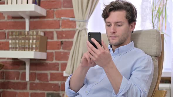 Young Man Using Smartphone in Modern Office