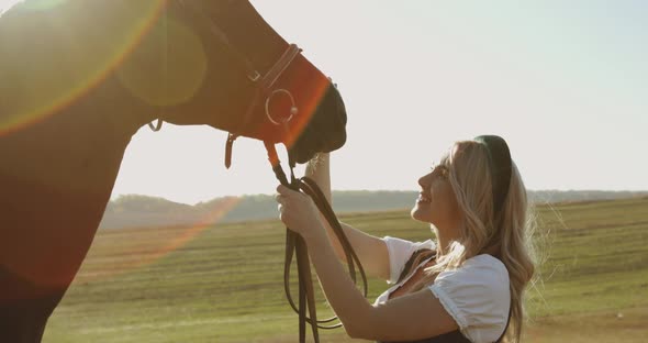 Portrait of Girl in a National Dress Caresses Brown Horse and Rejoices on Meadow