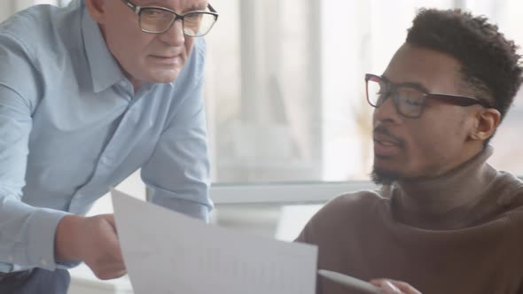 Black Male Analyst Explaining Performance Chart to Confused Executive