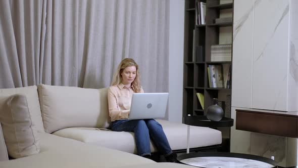 girl works at home with a laptop on the couch in the room. Online work