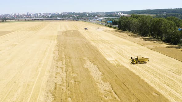 Aerial Drone Shot  Heavy Machinery (Combine Harvesters and a Truck) Work in a Field in a Rural Area