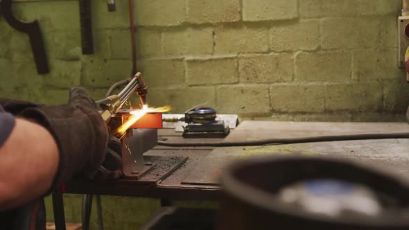 Caucasian male factory worker at a factory standing in a workbench and welding