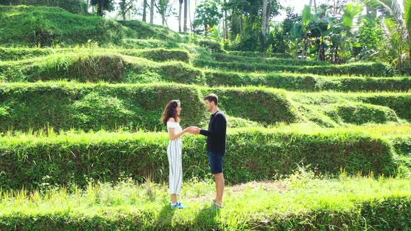 Young couple holding hands of each other standing on rice terraces, talking about vacation on exotic