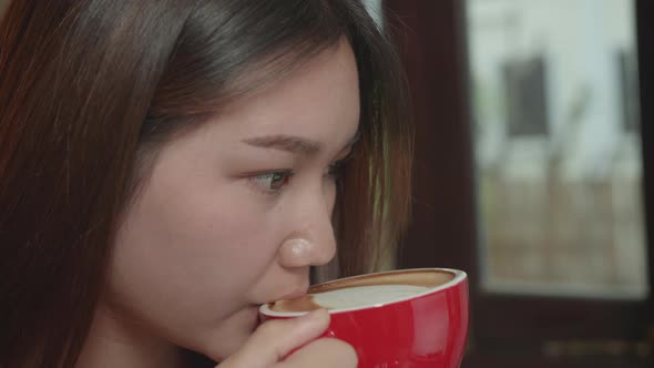 Asian Woman Holding And Drinking Hot Coffee In Cafe