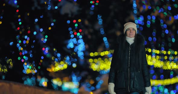 Beautiful Girl is Walking Along an Alley Decorated with Lights