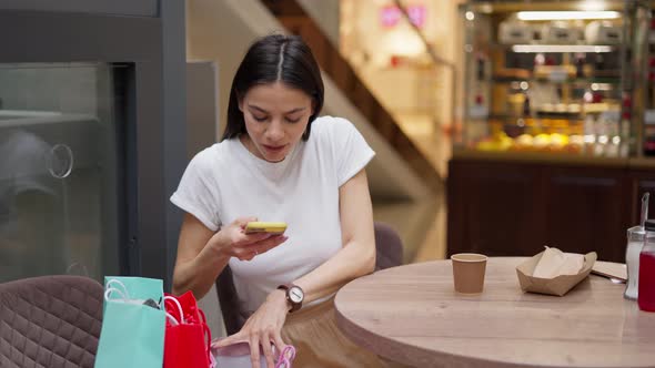 Woman Sending Pictures of New Purchases to Friends After Shopping Day in Mall
